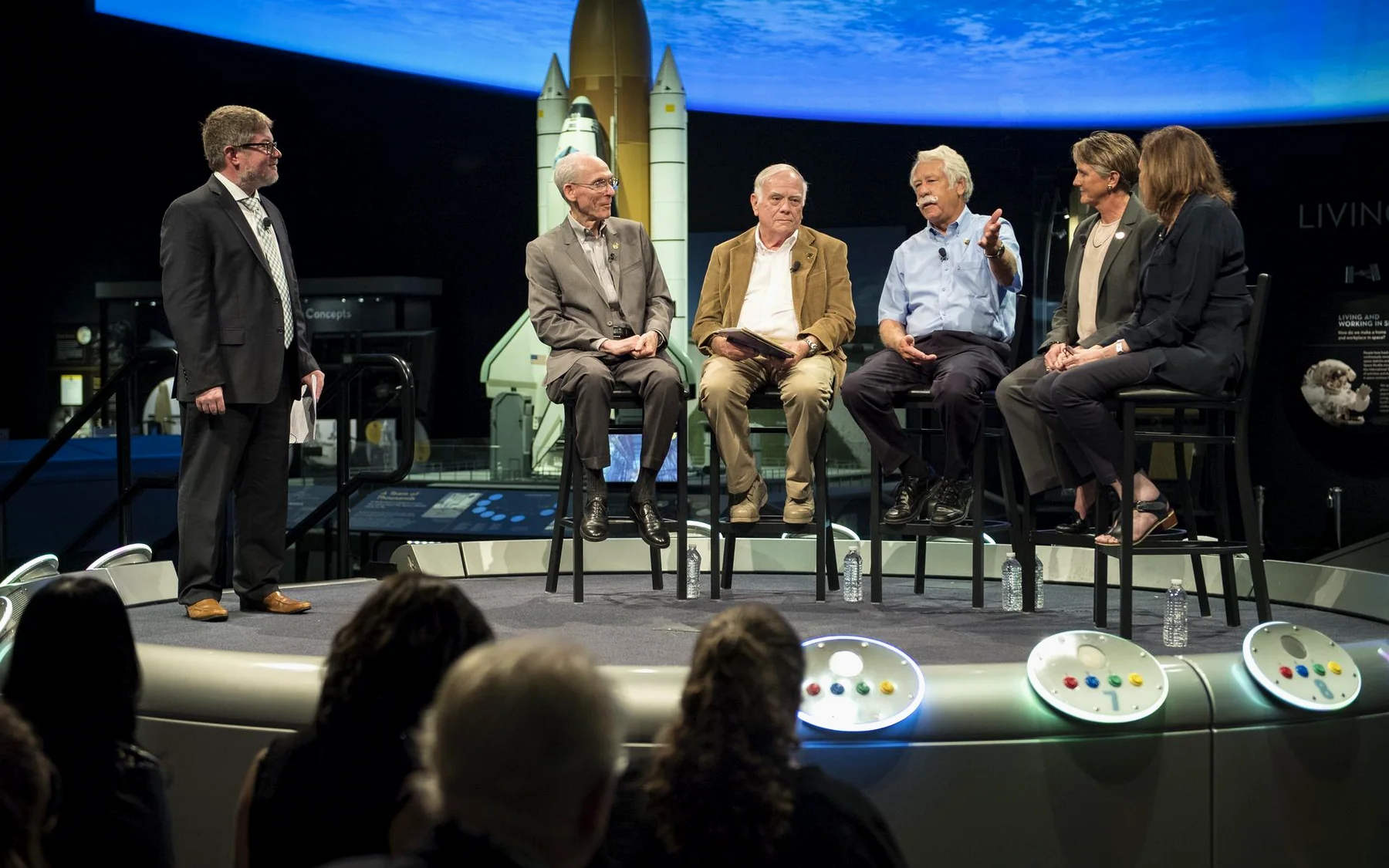 Panelists speaking on a stage in front of an audience